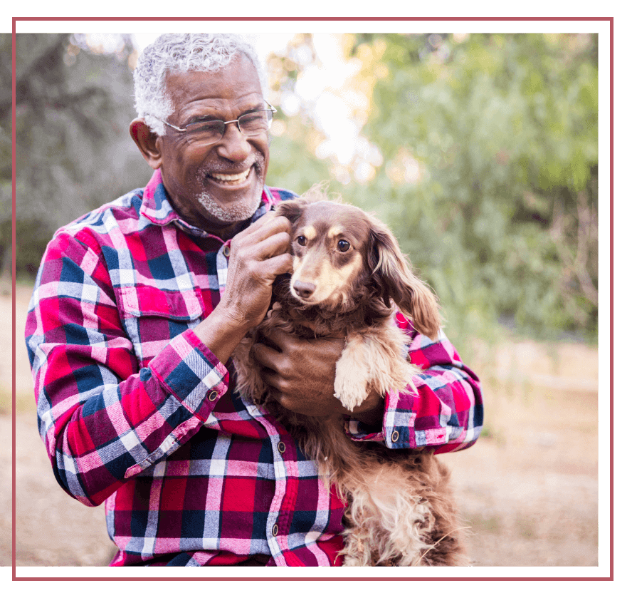 Senior man smiling and holding dog outside