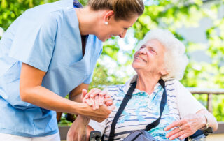 Senior woman sitting down, looking up at caregiver in assisted living community