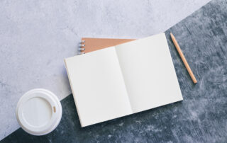 A journal on a table with coffee and a pen