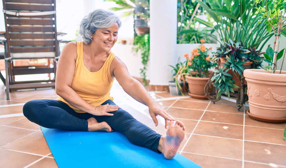 A senior woman stretches her leg to prevent falls