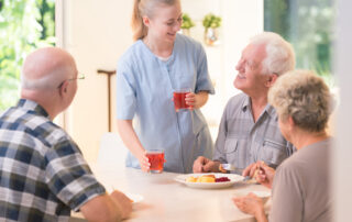 A memory care staff member serves breakfast to seniors