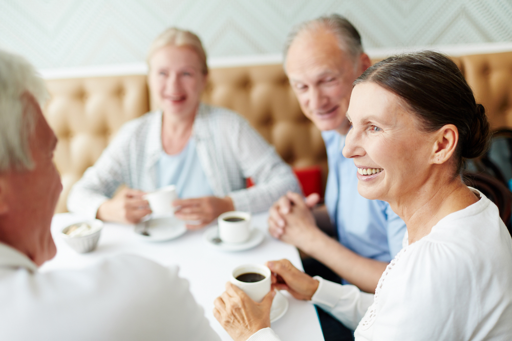 A group of senior friends talk while having coffee