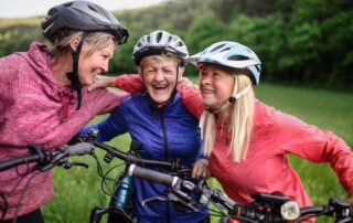 Happy, active senior women riding bikes together outdoors