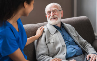 A senior man and a caregiver sit and talk on a couch at Canton senior living