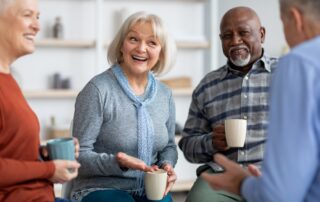 A happy group of senior friends socialize and drink coffee together