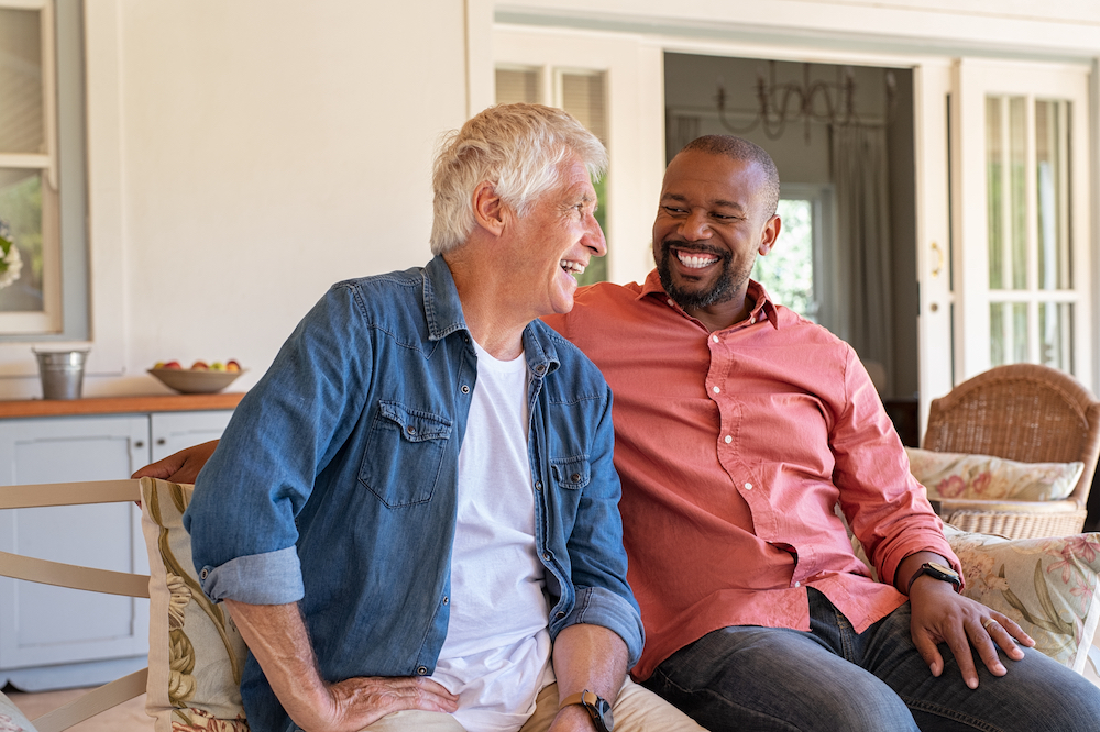 Two senior men sit and chat outside