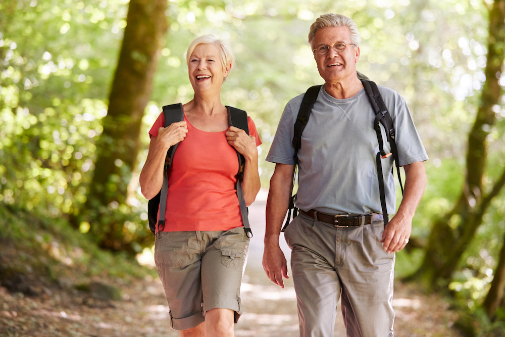 A senior couple hiking and walking outdoors in a park