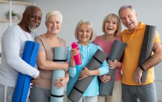 A group of active seniors holding yoga mats and chatting