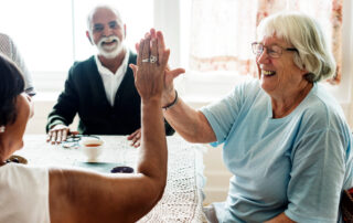 A group of senior friends laugh and share a high five at the best senior living in Canton, MI