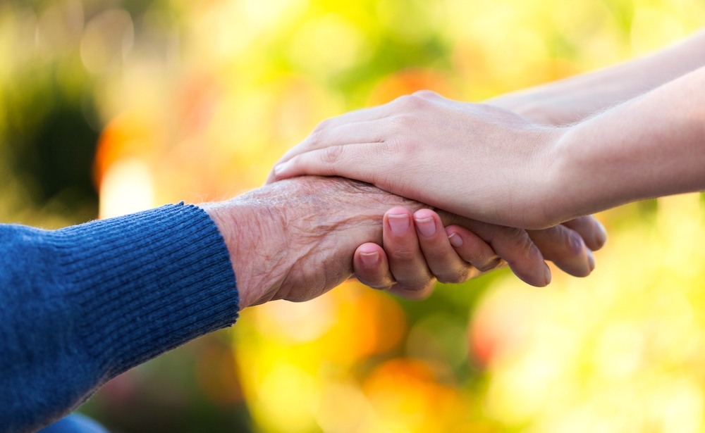 A caregiver holding hands with a senior woman