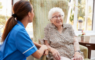 A senior woman sits and visits with a caregiver at best memory care facilities near me