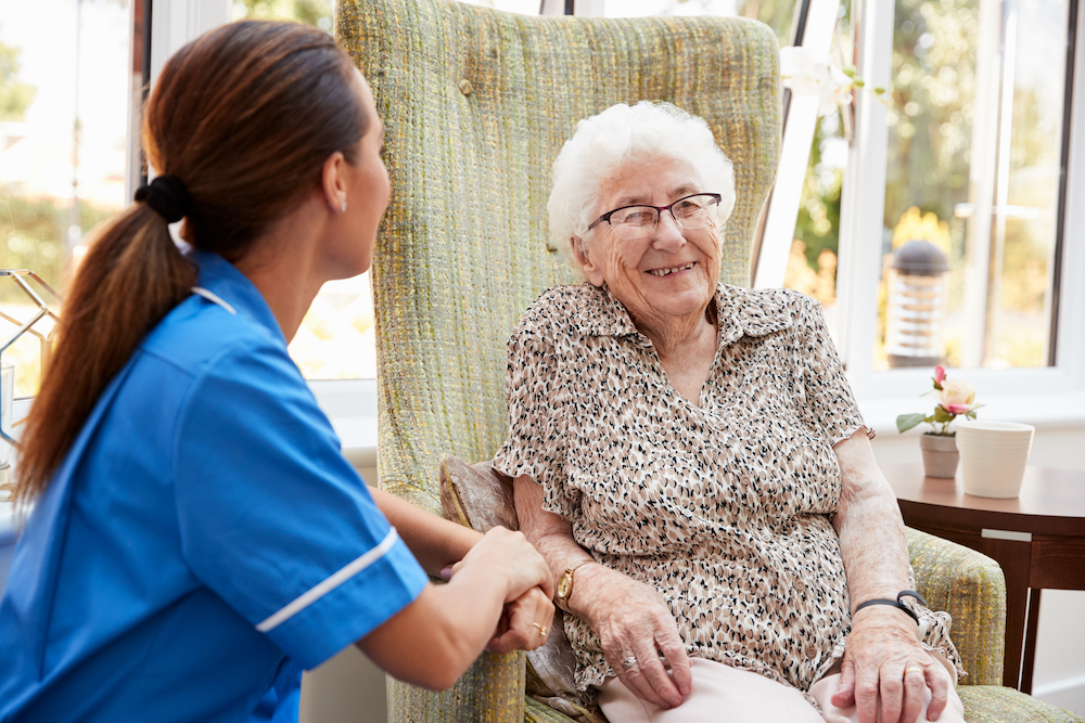 A senior woman sits and visits with a caregiver at best memory care facilities near me