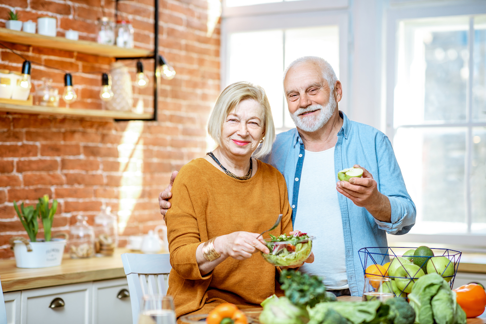 A cheerful senior couple prepare and eat healthy foods together