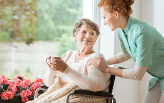 A senior woman drinking tea while talking to the staff at her senior living home