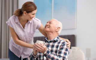 A female caregiver bringing a senior man a cup of tea