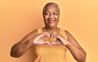 Senior woman making a heart with her hands while enjoying best senior living communities in mi