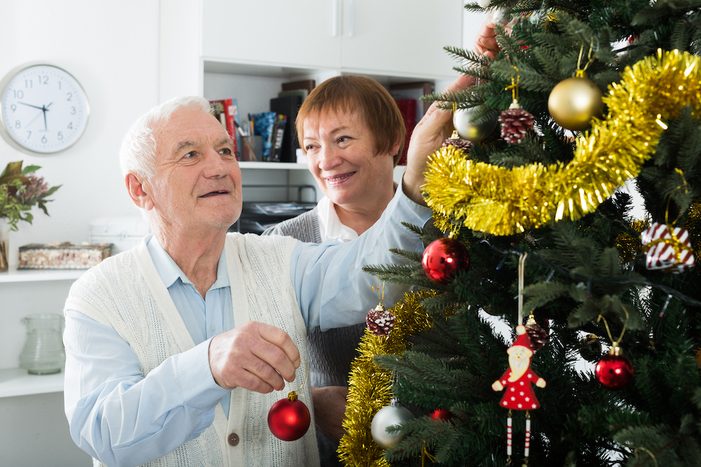 A senior decorating a holiday tree at their dementia senior living community