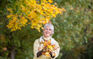 A senior woman holding a pile of leaves at the best assisted living near me