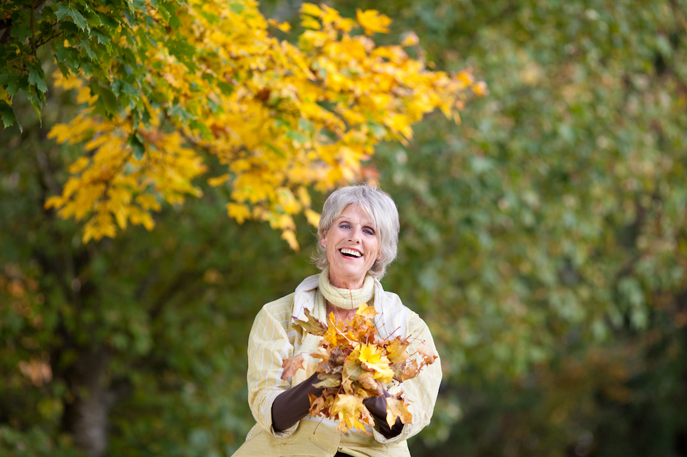 A senior woman holding a pile of leaves at the best assisted living near me
