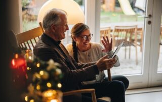 A senior man and daughter using a tablet to stay connected at a dementia senior living community