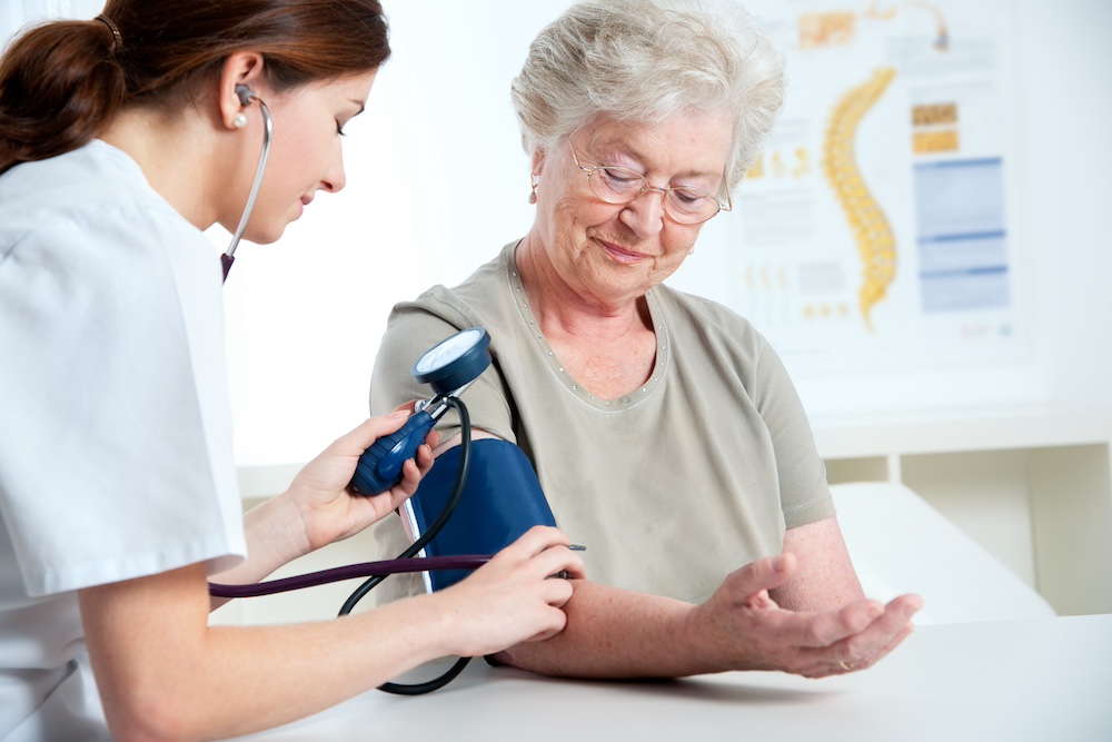 A senior woman gets her blood pressure checked by a doctor