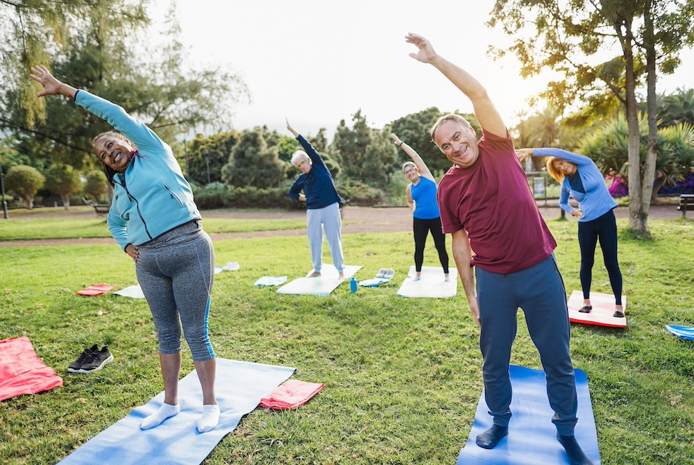A group of seniors participate in a yoga course outdoors