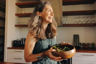 Senior woman holding salad bowl in dementia senior living.