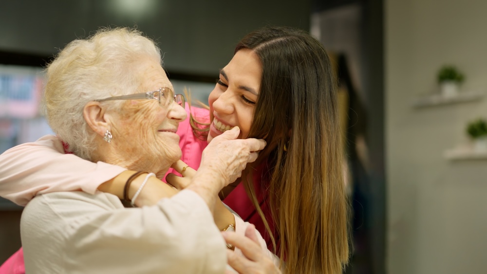 Senior woman hugging her caregiver at her memory care program