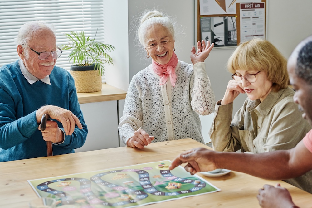 Group of seniors playing board game together while enjoying assisted living help for seniors 