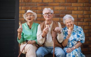 Senior friends outside on bench enjoying ice cream and assisted living help for seniors